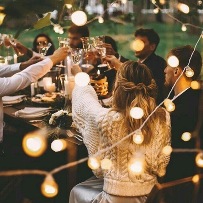 People celebrating at an outdoor dinner with string lights in Norway